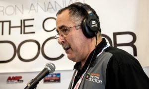 ron ananian on microphone in front of car doctor show banner